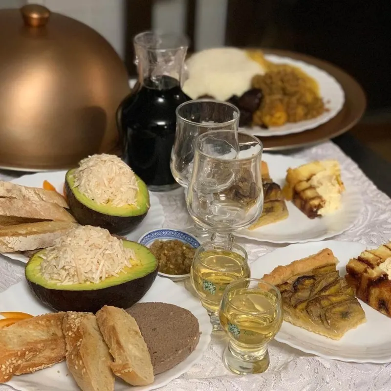 La table d'hôtes dressée : avocats garnis, pain, rhum arrangé et tarte à la banane